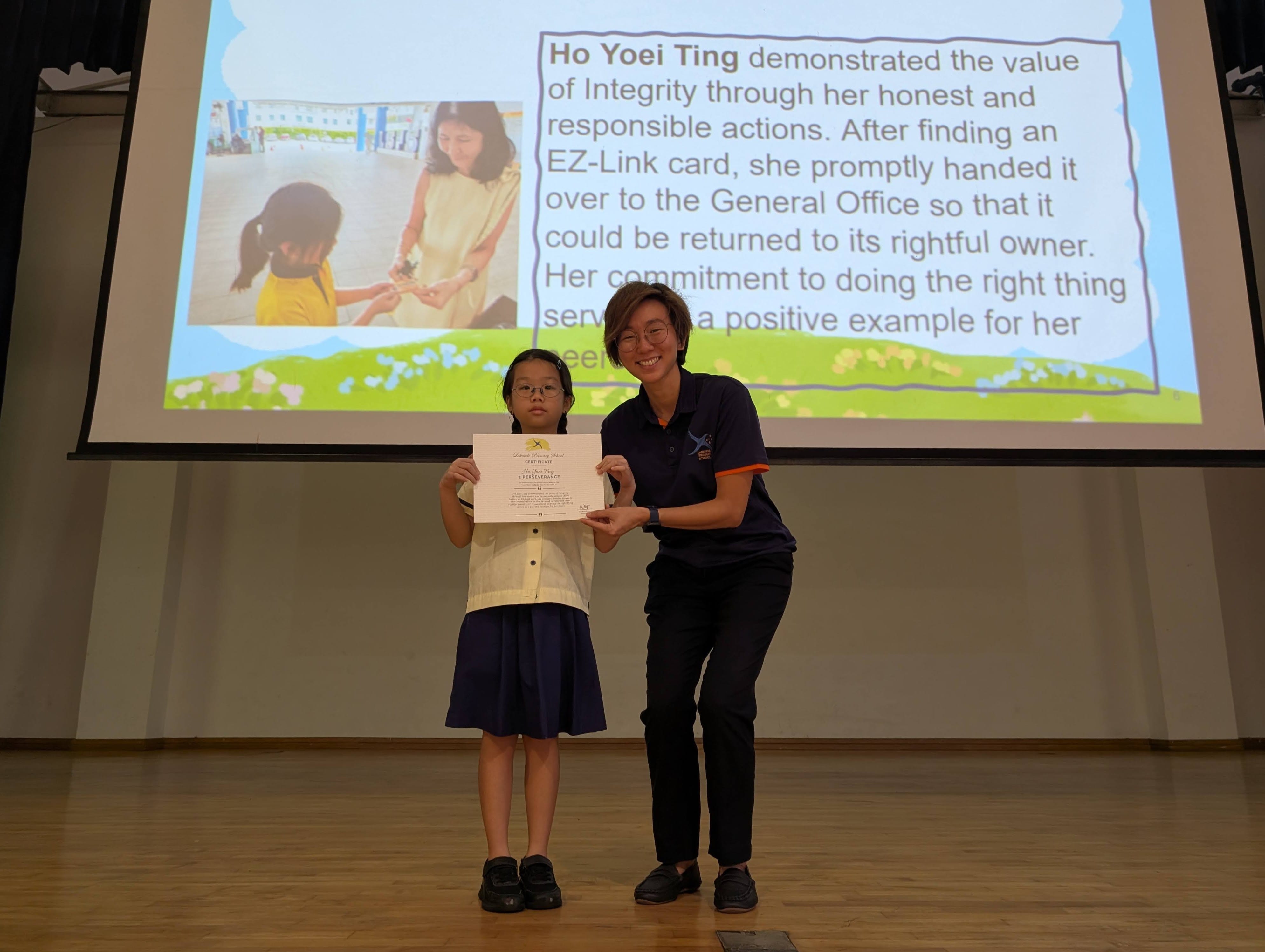 A girl receiving a certificate on the stage. 